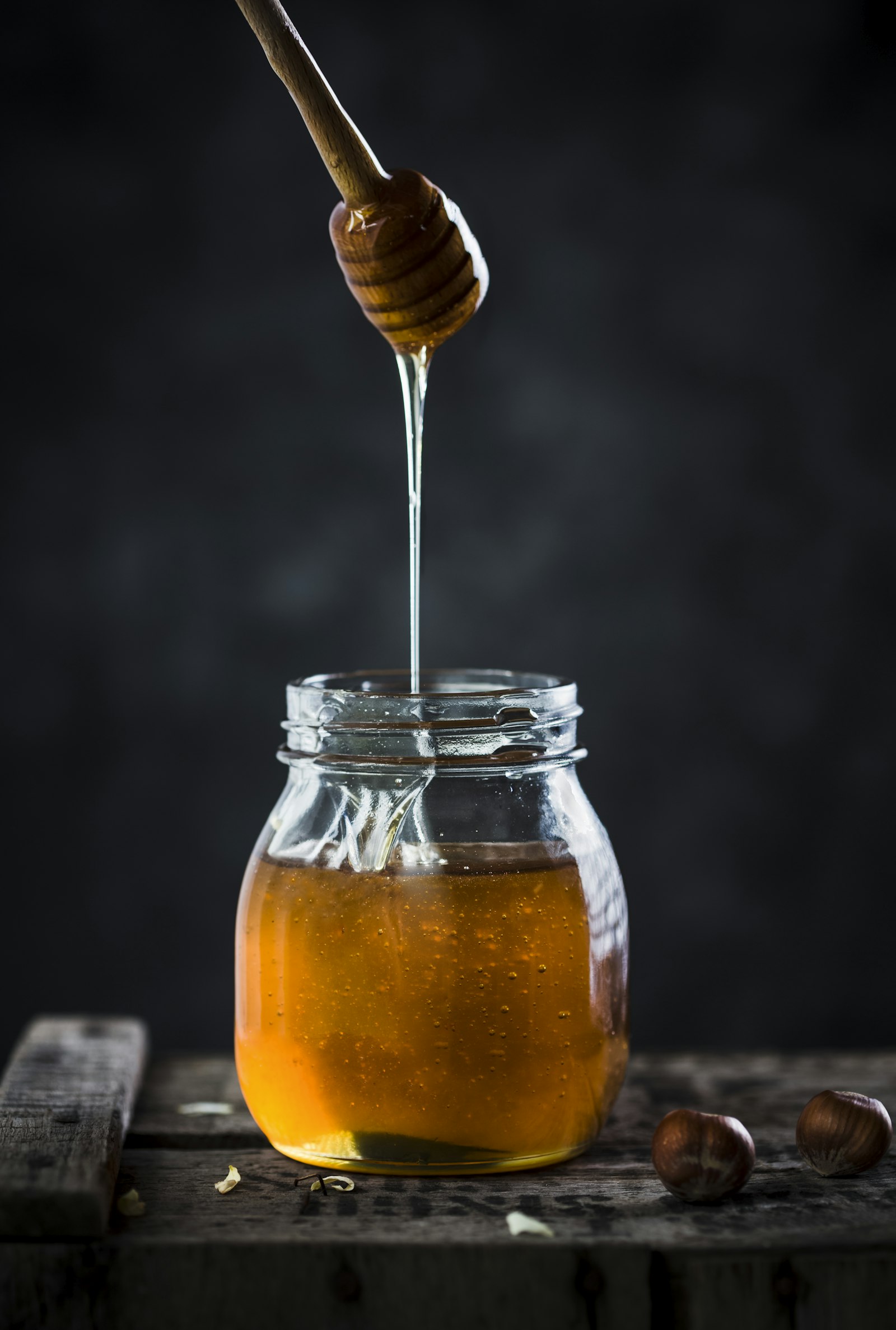 A jar of honey with a wooden spoon